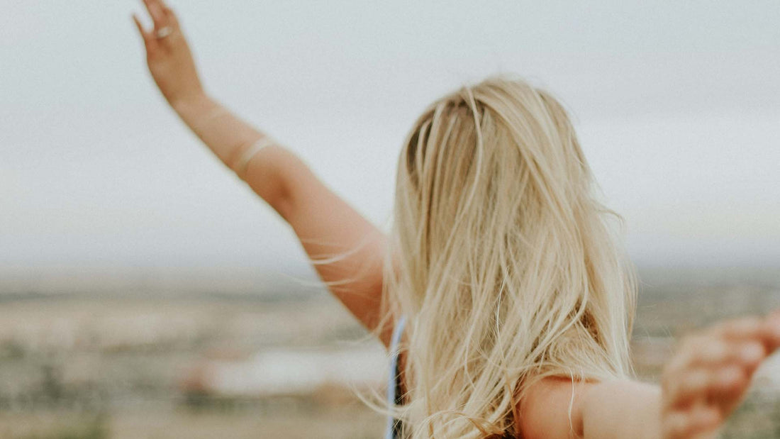 blonde woman standing in a field with arms outstretched