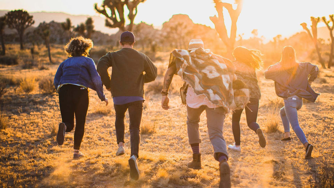 five friends running on the field near trees